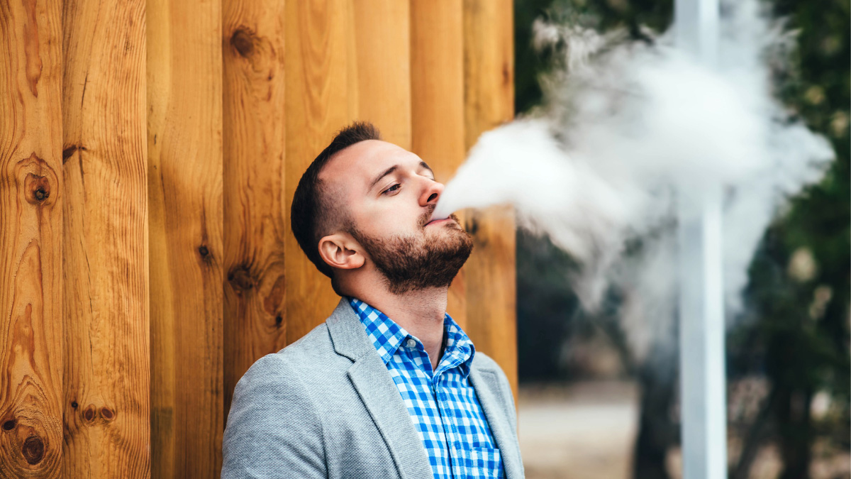 A man in a checkered jacket outside vaping THCa near Bogota, New Jersey.